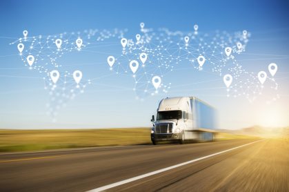 Truck driving on a highway with a digital world map overlay featuring location markers, symbolizing real-time shipment tracking and modern logistics technology.